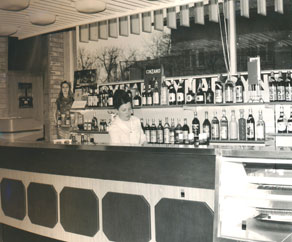 Čeprav je imela vsaka večja poslovalnica Alpkomerca tudi manjši bife za strežbo pijač je bilo gostinstvo do  osamosvojitve Slovenije za podjetje postranska dejavnost. Z združitvijo s podjetjema Gostinstvo Tolmin ter Hoteli Bovec pa sta pridobila gostinstvo in hotelirstvo znotraj družbe enak status, kot ga je imela dotlej trgovina. Fotografija prikazuje bife v prvi Alpkomercovi blagovnici v Tolminu. (Arhiv PANG)